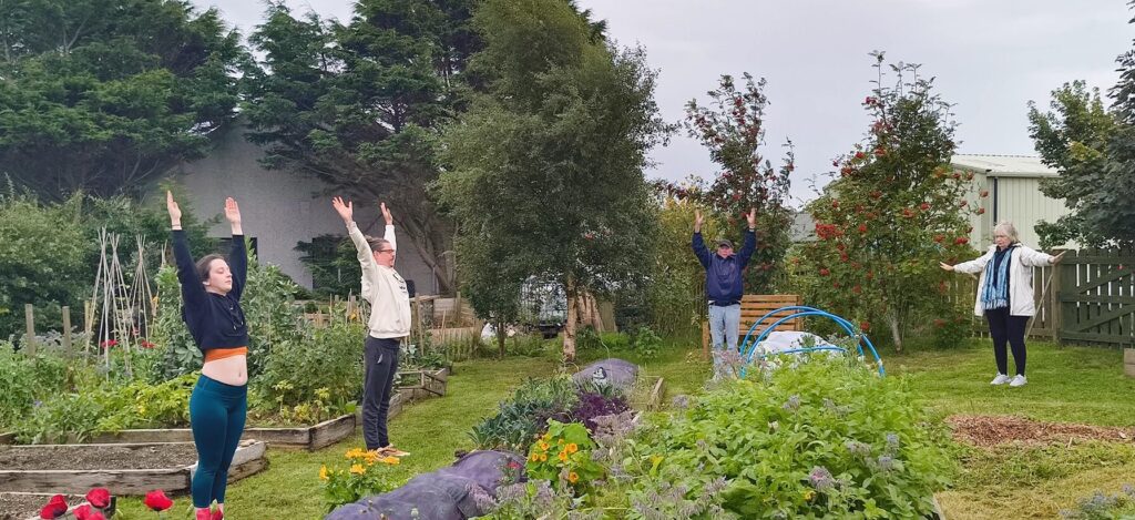 A group of people do yoga in a community garden