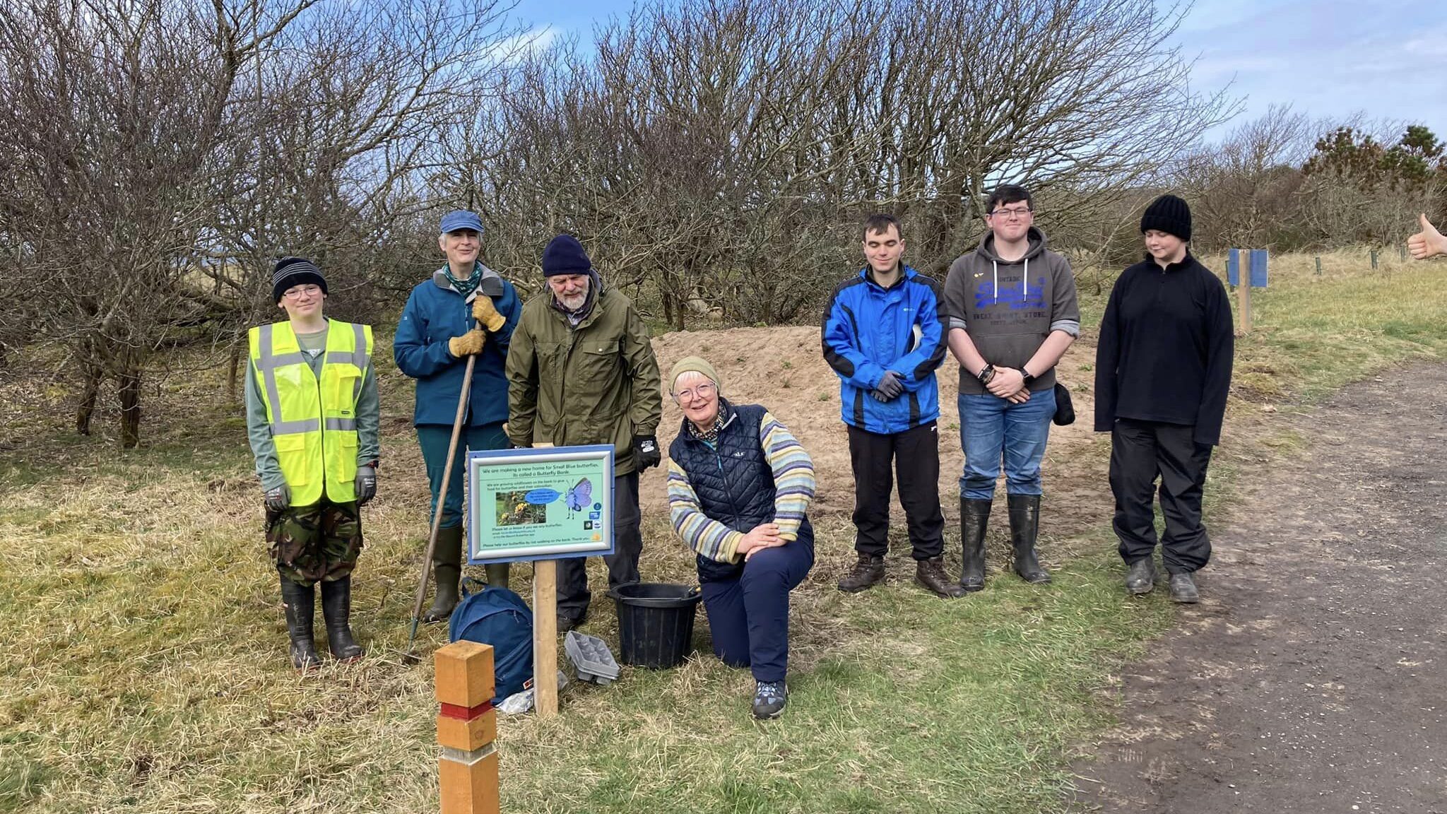 A group of volunteers smile for the camera in Dunnet Community Forest. They stand in front of a butterfly bank