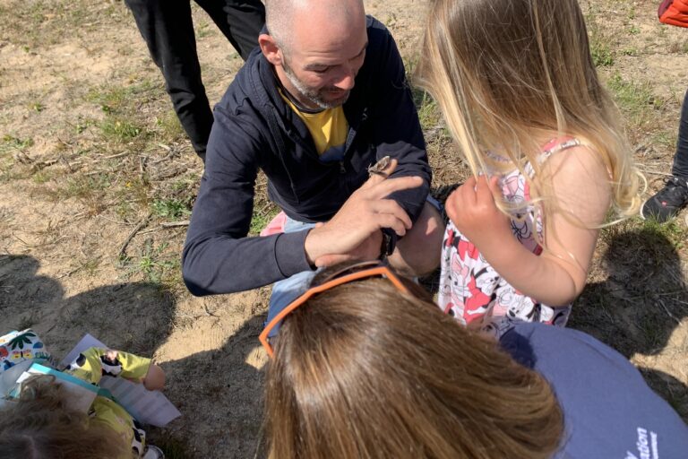 A man and some young girls look at a moth