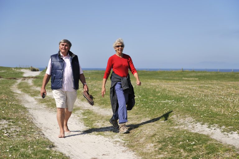 Two people walking on a track across the machair, South Uist